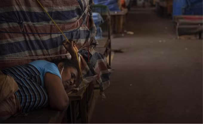 Một người bán rau ở Sri Lanka ngủ bên gian hàng của cô ấy tại một chợ rau bán buôn đã đóng cửa để hạn chế sự lây lan của Covid-19 ở Colombo, Sri Lanka. (Nguồn: Eranga Jayawardena/AP Photo).