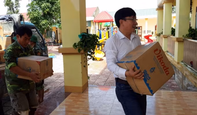 Nhà báo Nguyễn Xuân Hoàng cùng các thành viên đoàn cứu trợ và Bộ đội Biên phòng Hà Tĩnh mang hàng hóa, nhu yếu phẩm đến với bà con bị thiệt hại tại xã Cẩm Duệ - Ảnh: Chu Mùi
