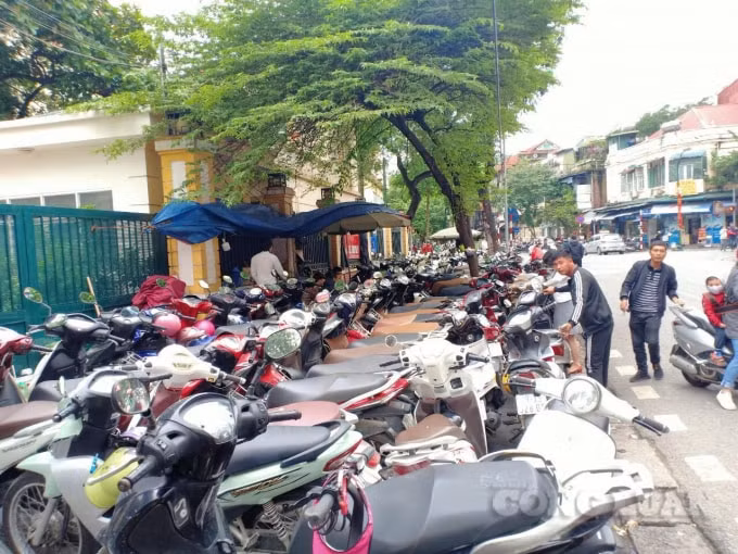 Bãi trông giữ xe lấn chiếm lòng lề đường trước cổng Bệnh viện Hữu Nghị Việt Đức .