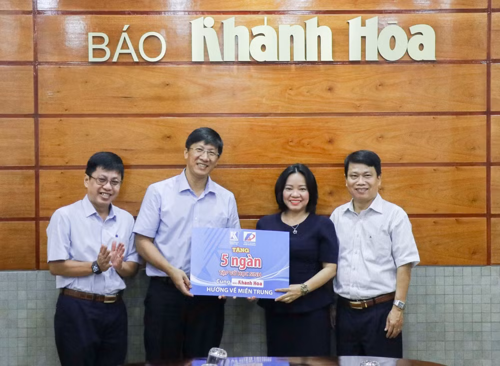 Ông Phan Trường Minh - Phó Giám đốc Công ty Cổ phần In Bao bì Khatoco (thứ 2 từ trái sang) trao tượng trưng 5.000 cuốn vở cho lãnh đạo Báo Khánh Hòa.