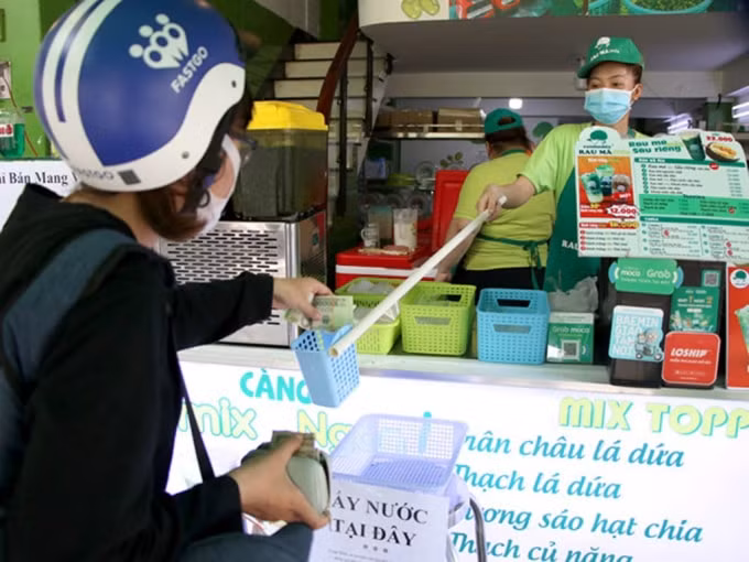 Một cửa hàng dùng cây sào dài và rổ để giao nhận tiền, hàng gián tiếp phòng dịch COVID-19. Ảnh minh họa