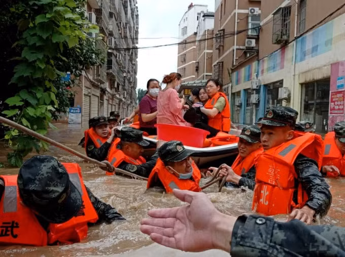 Các nhân viên cảnh sát bán quân sự sơ tán những người dân bị mắc kẹt trong nước lũ sau trận mưa lớn ở thị trấn Hedian của Tô Châu, tỉnh Hồ Bắc, Trung Quốc ngày 12 tháng 8 năm 2021 - Ảnh: REUTERS