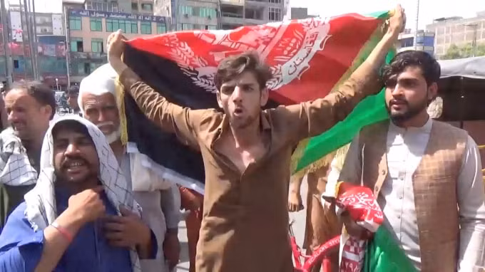 Người dân mang theo cờ Afghanistan khi họ tham gia một cuộc biểu tình chống Taliban ở Jalalabad, Afghanistan ngày 18 tháng 8 năm 2021 - Ảnh: Reuters