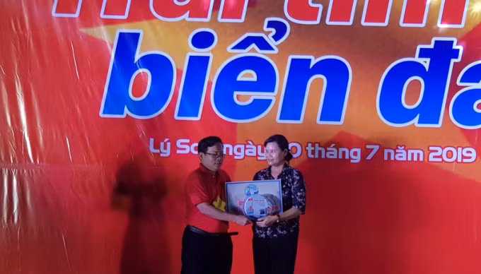 Ông Tô Đình Tuân - Tổng biên tập Báo Người Lao động trao cho bà Phạm Thị Hương - Phó Chủ tịch UBND huyện Lý Sơn 2.000 lá cờ Tổ quốc cùng ngư dân bám biển. Ảnh: Lê Bá Sơn