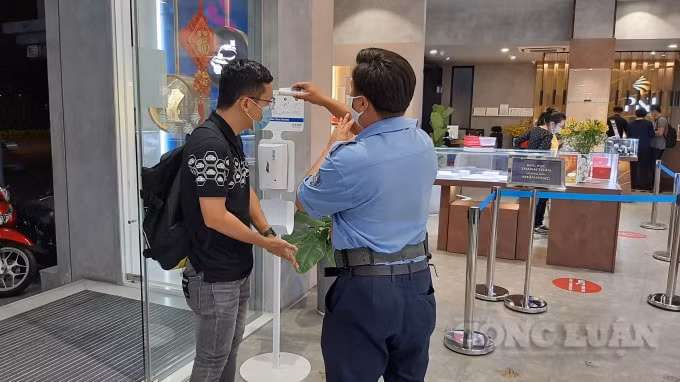 Khách đeo khẩu trang và đo thân nhiệt trước khi vào mua vàng