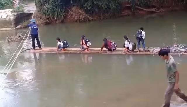 Người dân đưa các cháu nhỏ đi học qua suối bằng bè và sử dụng sức người để kéo bè qua sông. Ảnh CTV.