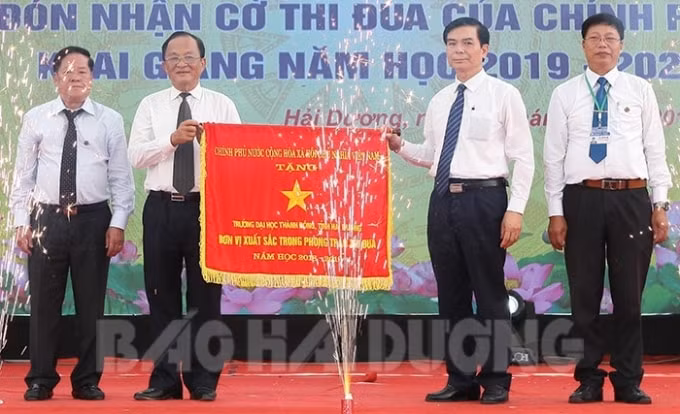 Thừa ủy quyền của Thủ tướng Chính phủ, đồng chí Vũ Văn Sơn, Phó Bí thư Thường trực Tỉnh ủy trao cờ thi đua xuất sắc cho Trường Đại học Thành Đông. Ảnh: H.D