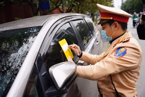 CSGT dán thông báo phạt nguội trên kính xe với chủ phương tiện. Ảnh: SGGP
