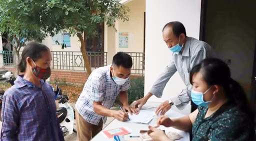 Chi trả tiền hỗ trợ cho hộ nghèo. Ảnh TTXVN.