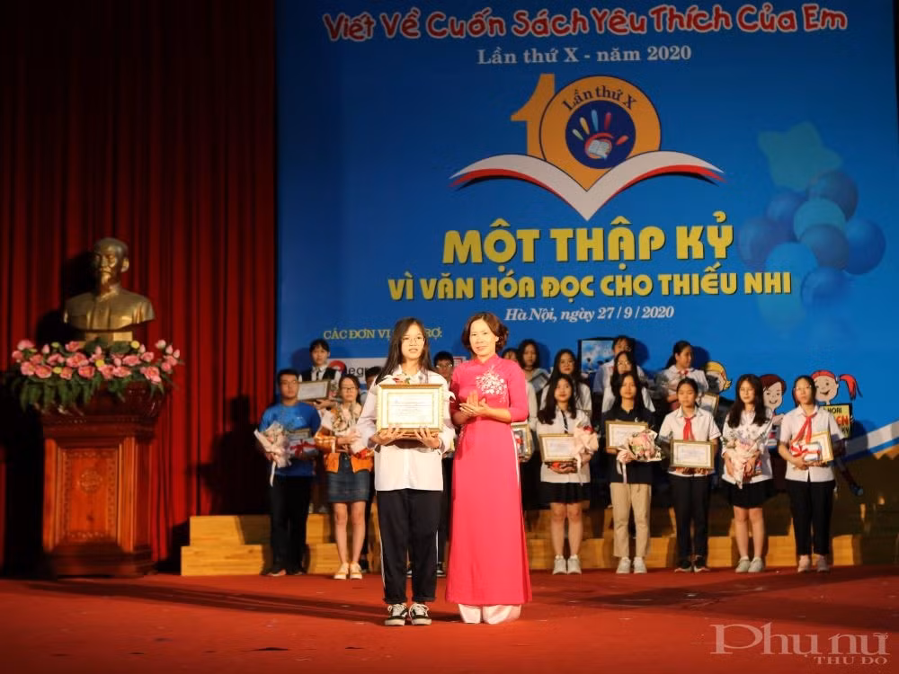 Bà Lê Kim Anh - Chủ tịch Hội LHPN Hà Nội trao giải Nhất cho tác giả Hoàng Minh Phúc - lớp 8A3, trường THCS Trung Hòa (Hà Nội), viết về tác phẩm “Dòng sông thơ ấu”. Ảnh: Nguyễn Thực