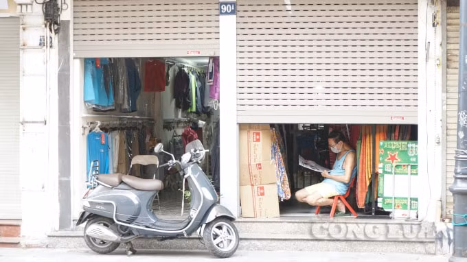 Một chủ cửa hàng trên phố Hàng Đào tranh thủ đọc báo. Ảnh H.Long.