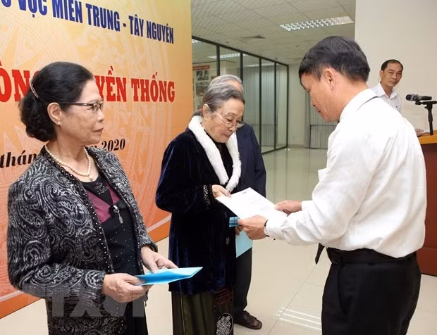 Tổng giám đốc TTXVN Nguyễn Đức Lợi trao tặng sổ tiết kiệm cho thân nhân, gia quyến 17 liệt sỹ, nhà báo của TTXVN đã hy sinh trên các chiến trường khu vực miền Trung-Tây Nguyên tại buổi lễ. (Ảnh: Trần Lê Lâm/TTXVN)