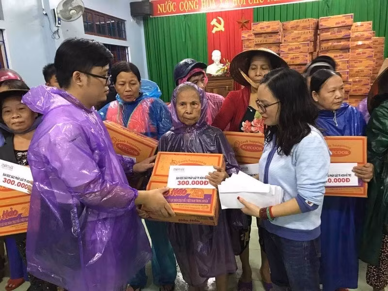 Báo Pháp Luật TP.HCM trao quà, tiền cho một người dân giữa vùng nước lũ.