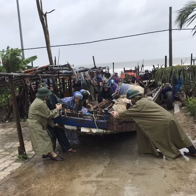 Lãnh đạo địa phương giúp ngư dân di chuyển thuyền vào nơi tránh bão. Ảnh: Quang Duy