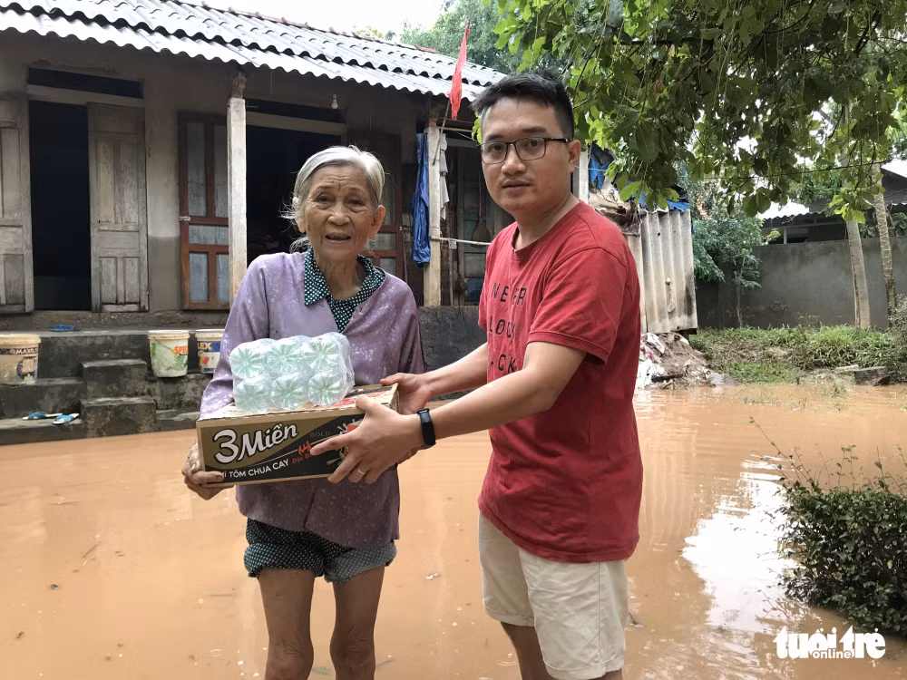 Phóng viên báo Tuổi Trẻ tác nghiệp tại vùng lũ Triệu Phong và trao hỗ trợ cho bà Nguyễn Thị Liễu, 79 tuổi ở thôn Dương Lệ Đông, xã Triệu Thuận, huyện Triệu Phong hộ nghèo, sống với con tâm thần - Ảnh: Đoàn Nhạn