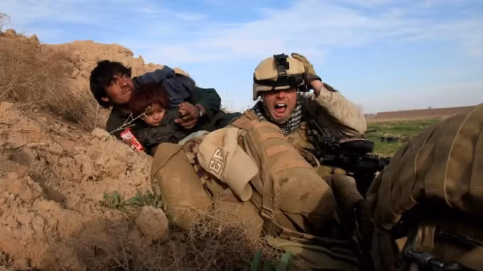 Một lính thủy đánh bộ Mỹ hét lên khi anh ta cố gắng bảo vệ một người đàn ông Afghanistan và đứa con của anh ta sau khi các tay súng Taliban nổ súng ở thị trấn Marjah, thuộc tỉnh Helmand, Afghanistan. © Reuters