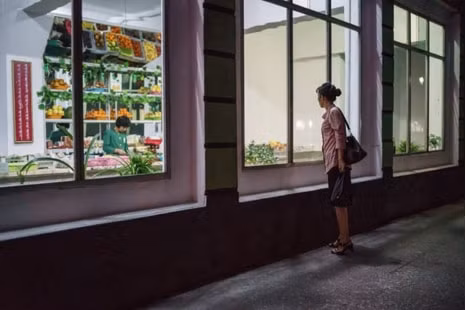 Một phụ nữ đứng bên ngoài cửa hàng tạp hóa trên đường phố ở Bình Nhưỡng. (Nguồn: AFP Photo).