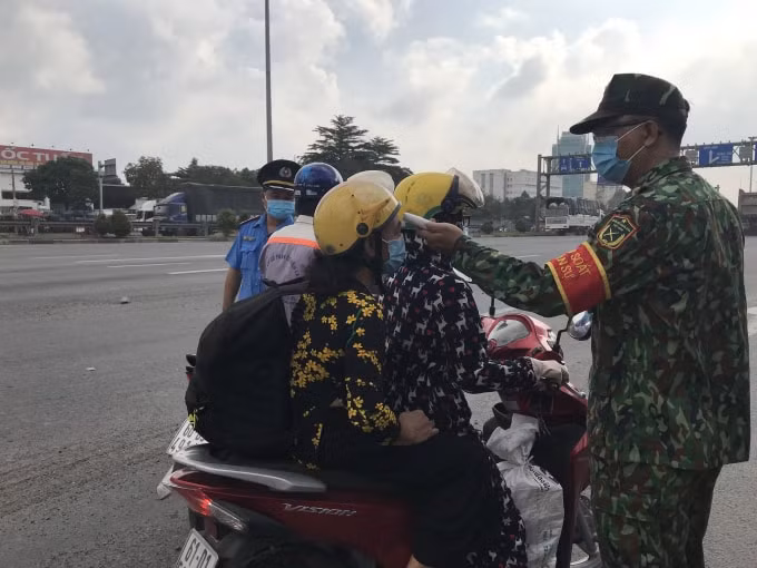 Lực lượng chức năng kiểm tra thân nhiệt người đi đường tại chốt kiểm soát phòng chống dịch bệnh Covid-19.