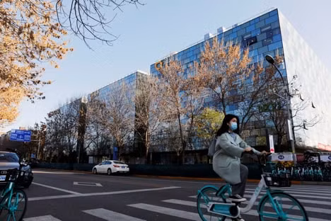 Một người phụ nữ đi xe đạp chung Didi qua trụ sở của Didi Chuxing ở Bắc Kinh, Trung Quốc ngày 20 tháng 11 năm 2020. (Nguồn: REUTERS/Florence Lo/Photo).