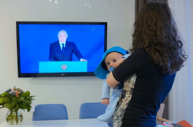 Người phụ nữ xem trực tiếp bài phát biểu của Tổng thống Putin trước Quốc hội Liên bang. Thứ 4, ngày 21 tháng 4 năm 2021 - Ảnh: Sputnik