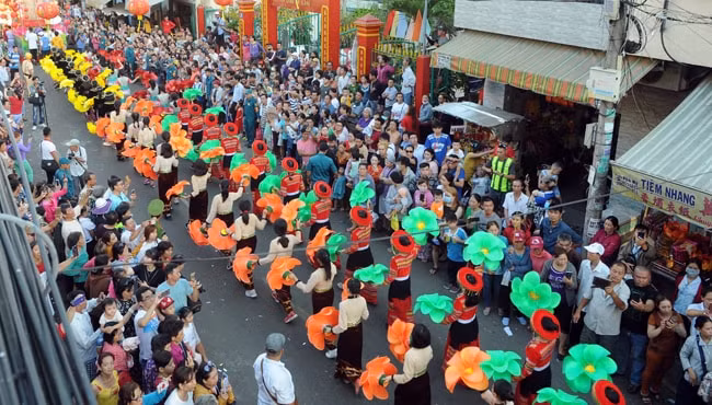 Đông đảo người dân đứng hai bên đường để theo dõi đoàn nghệ thuật diễu hành đi ngang qua.