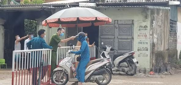Cán bộ Công an kiểm tra thân nhiệt những người vào khu phố Nam Bắc, phường Quảng Vinh