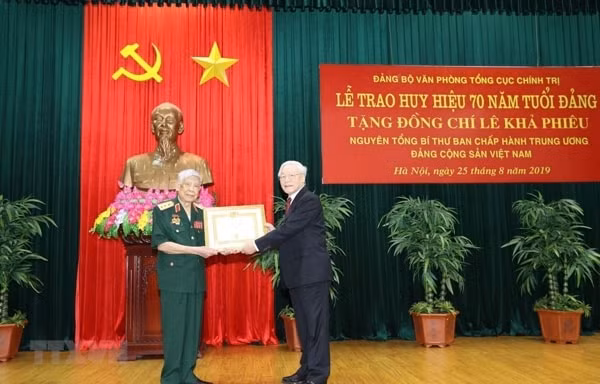 Tổng Bí thư, Chủ tịch nước Nguyễn Phú Trọng, Bí thư Quân ủy Trung ương trao Huy hiệu 70 năm tuổi Đảng tặng nguyên Tổng Bí thư Lê Khả Phiêu. Ảnh: TTXVN