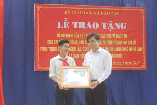 Đại diện Bộ GDĐT trao bằng khen của Bộ trưởng Bộ GDĐT cho em Vũ Văn Hùng (Ảnh: Hà Đồng)