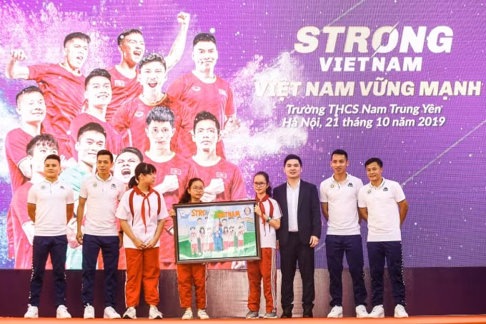 Các cầu thủ CLB bóng đá Hà Nội và Trưởng Ban tổ chức chương trình “Strong Vietnam” Đỗ Vinh Quang nhận quà là bức tranh từ các em học sinh THCS Nam Trung Yên.