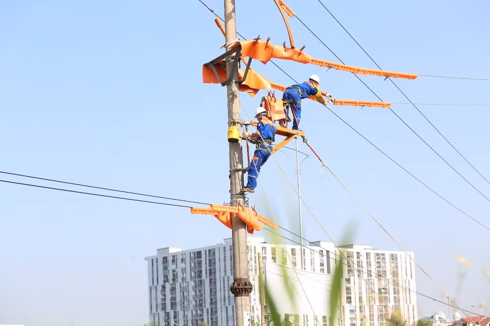 Bất chấp nền nhiệt hiện trường có thể lên tới 50°C, những người thợ "áo cam" vẫn khoác trên mình bộ trang phục bảo hộ cách điện nặng nề, tập trung cao độ cho từng thao tác.