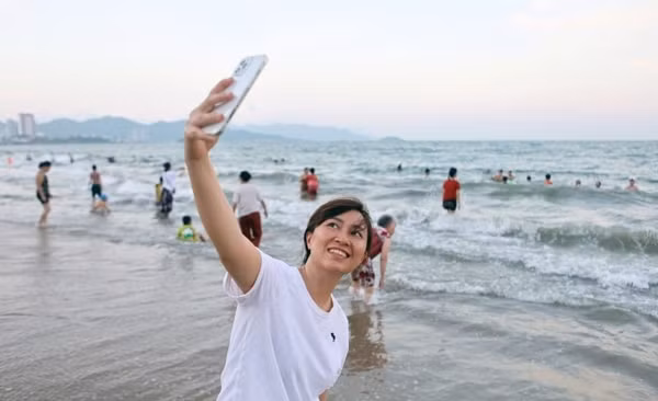 Chiều 30/4/2021, hàng nghìn người dân và du khách đổ về bãi biển TP Nha Trang tắm và vui chơi, phần lớn không đeo khẩu trang. Ảnh: VNE