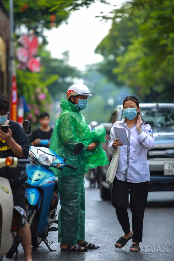 Một phụ huynh đưa con đến điểm trường thi sáng nay tỏ ý mừng rỡ khi đến giờ các con đi thi thì trời tạnh mưa.
