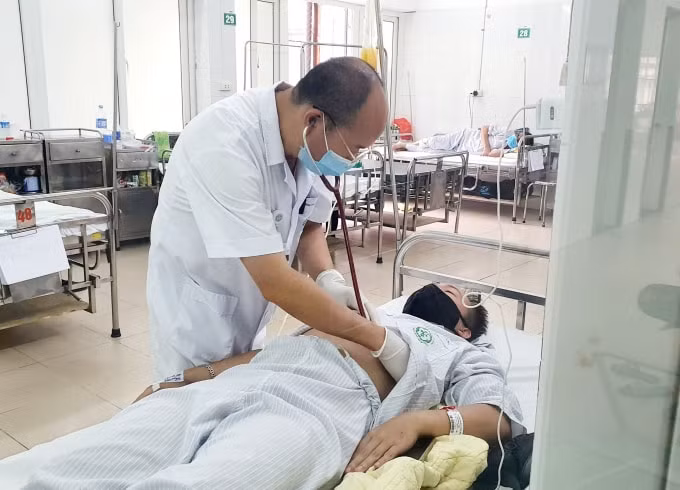 PGS.TS Đỗ Duy Cường thăm khám cho bệnh nhân tại Trung tâm bệnh nhiệt đới, Bệnh viện Bạch Mai (ảnh TL).