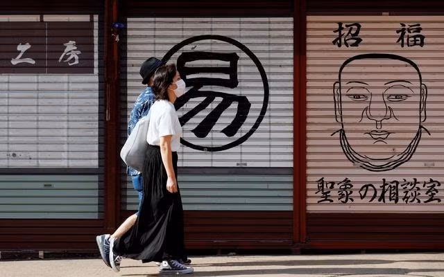 Hai người dân đi bộ ở Tokyo, Nhật Bản - Ảnh: Reuters
