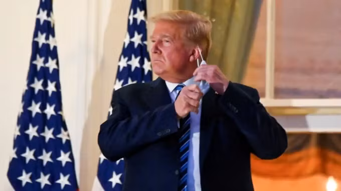 Donald Trump tháo khẩu trang trên ban công của Nhà Trắng sau khi trở về từ bệnh viện sau điều trị COVID. © Reuters