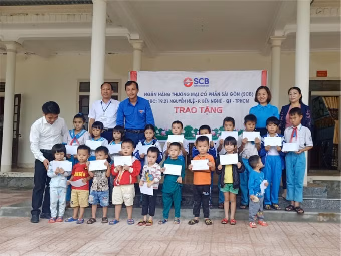 Đại diện SCB trao quà và phần tiền ủng hộ cho các em học sinh mầm non và tiểu học Hồng Lộc, Thụ Lộc, huyện Lộc Hà, tỉnh Hà Tĩnh.