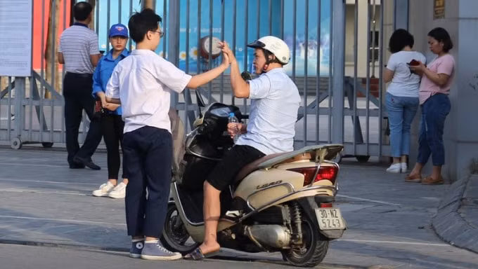 Phụ huynh giấu nỗi lo lắng để động viên con trước giờ thi. Ảnh: TL.