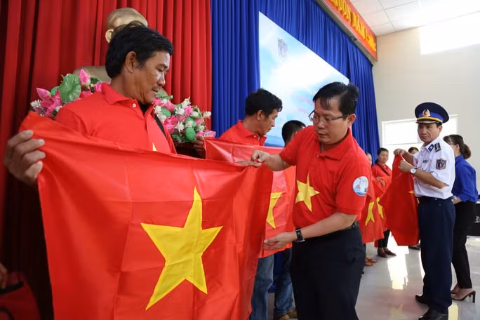 Ông Tô Đình Tuân, Tổng biên tập Báo Người Lao Động và Đại tá Lê Huy Sinh, Chính ủy Bộ Tư lệnh Vùng Cảnh sát biển 2 trao cờ Tổ quốc cho ngư dân huyện Núi Thành(ảnh: baonguoilaodong).