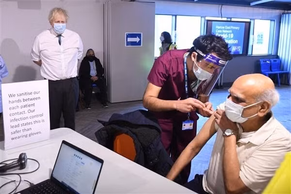 Thủ tướng Anh Boris Johnson (trái) thị sát việc tiêm phòng vaccine ngừa COVID-19 Astrazeneca tại The Hive, phía Bắc London, ngày 25/1/2021. Ảnh: AFP/TTXVN