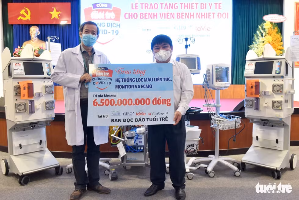 Ông Lê Thế Chữ - tổng biên tập báo Tuổi Trẻ (bên phải) - trao bảng tượng trưng cho ông Nguyễn Văn Vĩnh Châu - giám đốc Bệnh viện Bệnh nhiệt đới TP.HCM - Ảnh: Duyên Phan