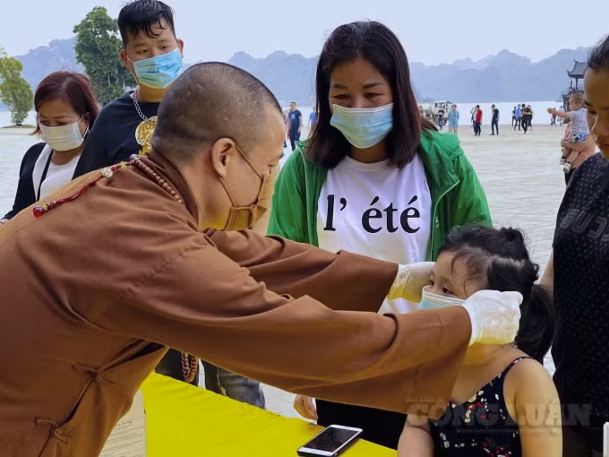 Thượng toạ Thích Minh Quang - phó trụ trì Chùa phát khẩu trang cho du khách ở các điểm đông người qua lại tại cổng Tam Quan Nội và điện Tam Thế.