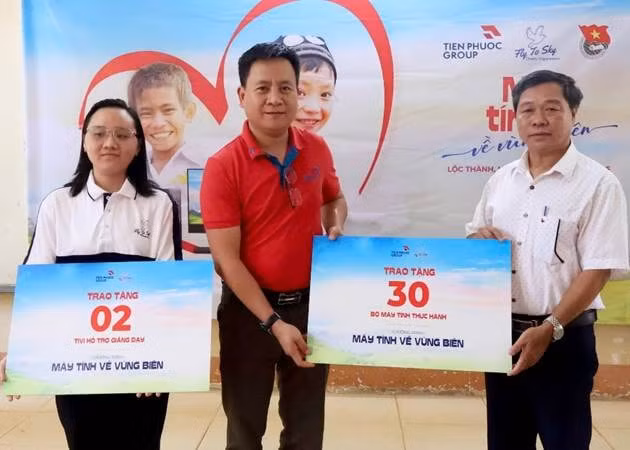 Ông Trần Hải Nam (áo đỏ) đại diện Tập đoàn Tiến Phước trao tặng biểu trưng cho Ban Giám hiệu trường Lộc Thịnh (ngoài cùng bên phải).
