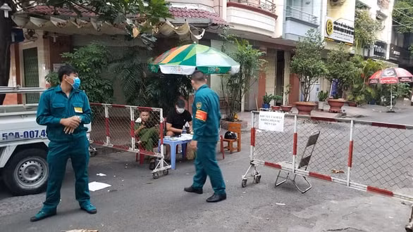 Lực lượng chức năng lập hàng rào cách ly và canh gác khu vực chung cư nơi bệnh nhân 92 đang ở. Ảnh TL.