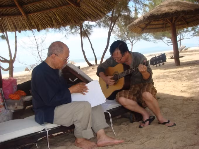 Họa sĩ Hoàng Ngọc Biên (bên trái) cùng với người bạn thân đang dạo bản nhạc mới do ông sáng tác. (Ảnh: Họa sĩ Đoàn Mẫn cung cấp).