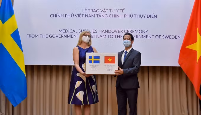 Thứ trưởng Ngoại giao Tô Anh Dũng trao tượng trưng 100.000 khẩu trang vải kháng khuẩn chống giọt bắn do Việt Nam sản xuất đến Đại sứ Thụy Điển tại Việt Nam Ann Mawe.