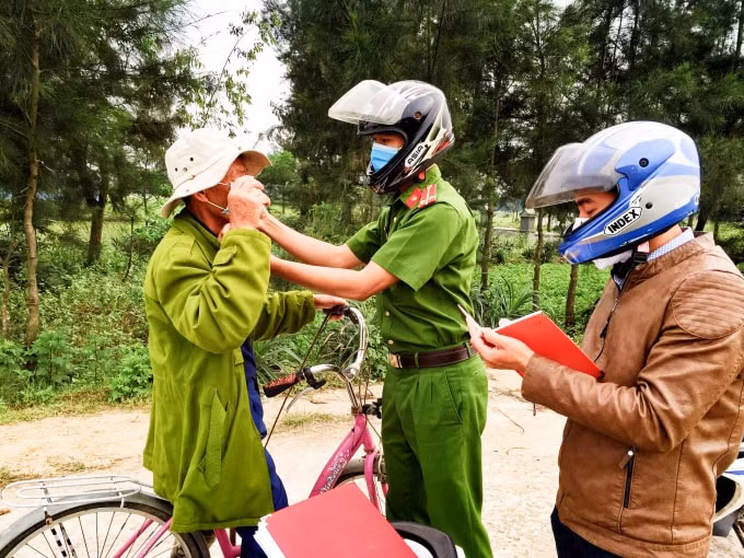 Phóng viên Đức Điệp cùng các lực lượng công an xã tuyên truyền nhắc nhở và phát khẩu trang miễn phí cho người dân trên địa bàn. Ảnh: Trần Phong