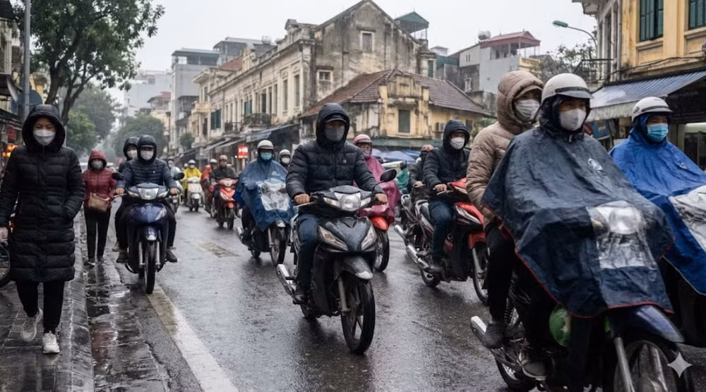 Người dân Hà Nội mặc áo ấm, trùm áo mưa kín mít di chuyển khó khăn trong cơn mưa phùn và gió lạnh sáng 31-1