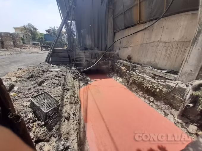 Dòng nước có màu đỏ chảy qua các kênh, mương dẫn xung quanh làng nghề giấy Phong Khê chảy trực tiếp ra sông Ngũ Huyện Khê. Ảnh H.Long.