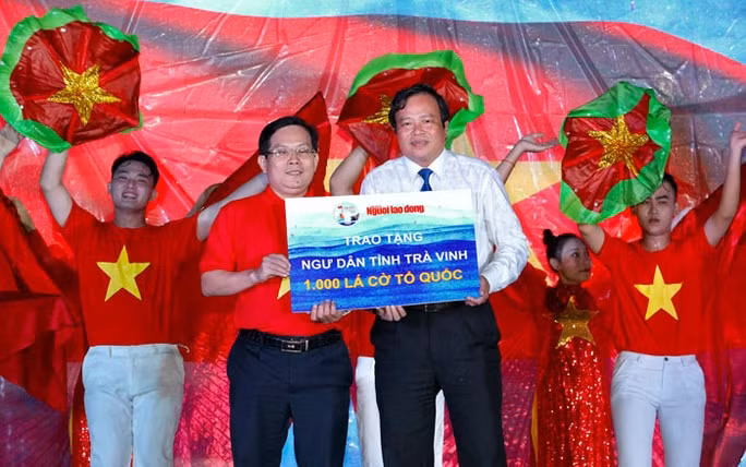 Ông Lê Văn Hẳn, Phó Chủ tịch UBND tỉnh Trà Vinh (bên phải), nhận bảng tượng trưng 1.000 lá cờ Tổ quốc do ông Tô Đình Tuân, Tổng Biên tập Báo Người Lao Động, trao tặng. Ảnh: Hoàng Triều
