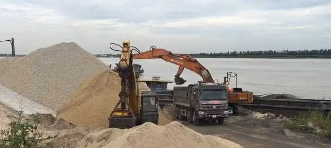 Những chuyến tàu chở than của Công ty TNHH DV&TM Hoàng Anh vẫn cập bến xã Mai Động, rìa sông là những đống vật liệu xây dựng lớn không được giải tỏa.